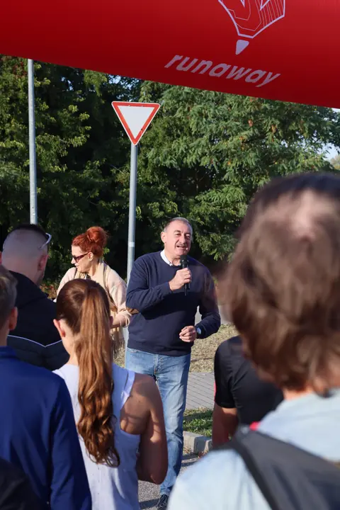 Megnyitó beszéd mikrofonnal a rajtkapunál a felsorakozott futók előtt