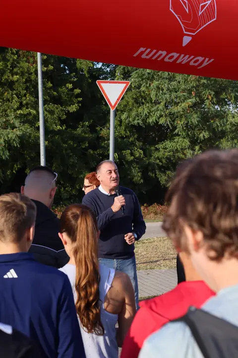 Rajt előtti köszöntő a rajtkapu alatt, előtérben a futók