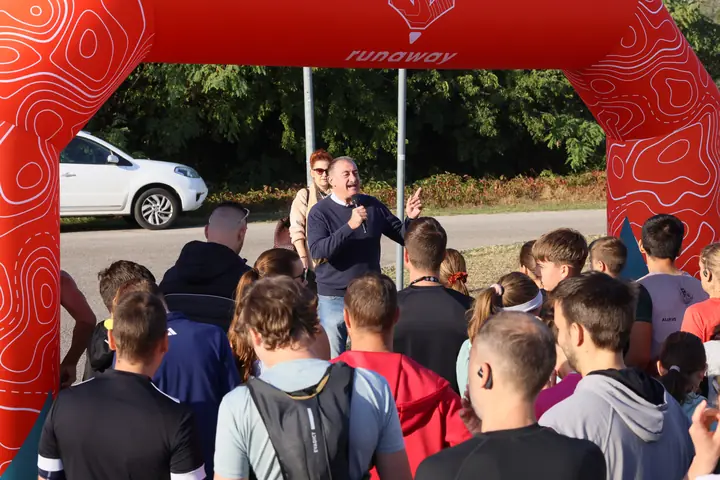 A futók hallgatják a rajt előtti köszöntőt a narancssárga kapu alatt