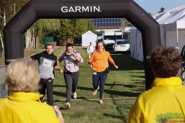 Futók érkeznek a fekete Garmin célkapun át, előtérben a segítők