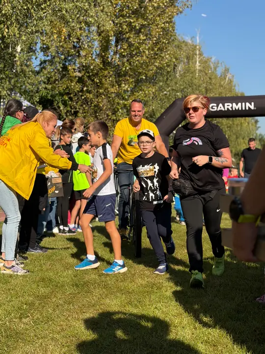 Gyerekek és felnőtt kísérők futnak a célkapu után