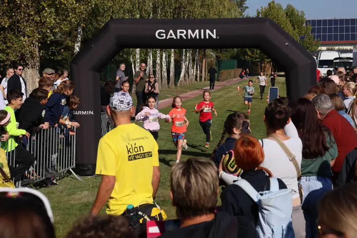 Célba érő gyerekek a Garmin kapunál, előtérben a segítő