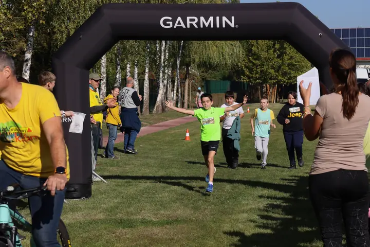 Gyerekek futnak át a Garmin célkapun, szurkolókkal a pálya mellett