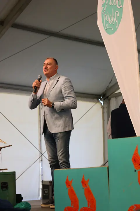 Eredményhirdetés: a műsorvezető mikrofonnal a színpadon