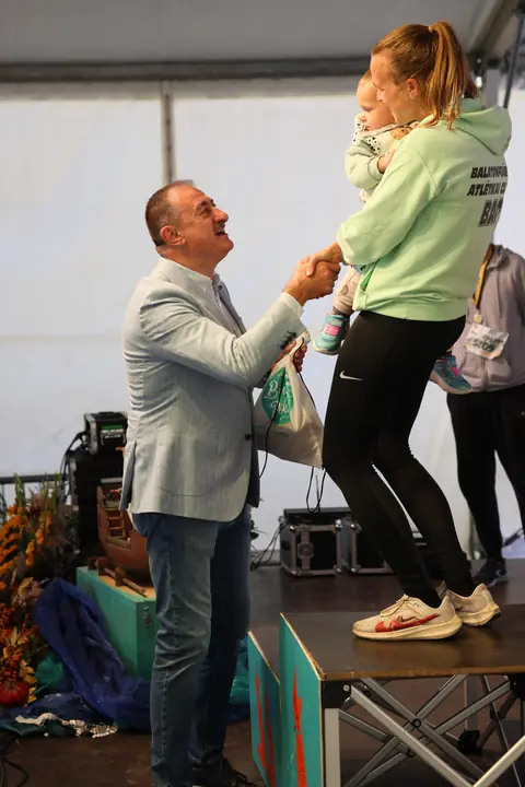 Díjátadás a színpadon, a dobogóra lépő fiatal futóval